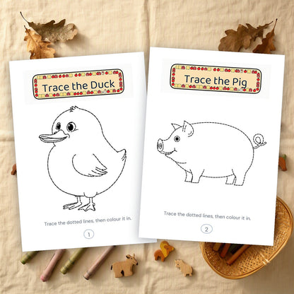 Two printed tracing pages, a duck and a pig in dashed outline, on a linen cloth