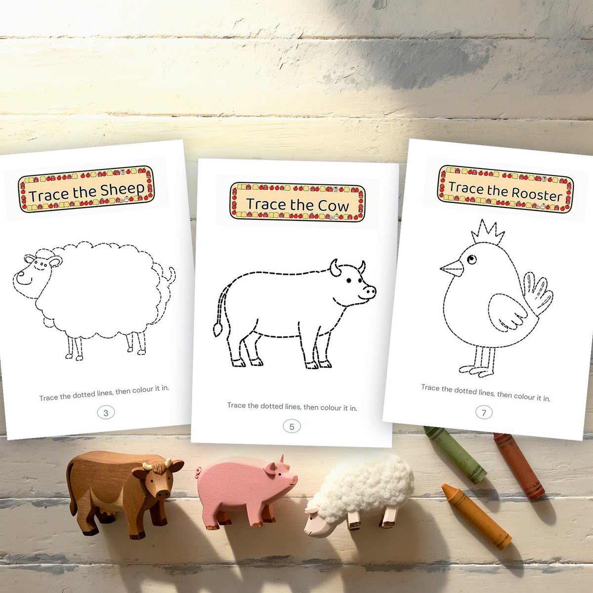Three printed tracing pages - sheep, cow and rooster - beside wooden farm animal toys